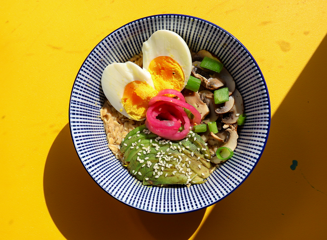 Miso Mushroom Savoury Oats in a bowl with a boiled egg, pickled onion, sautéed mushrooms, avocado and sesame seeds.