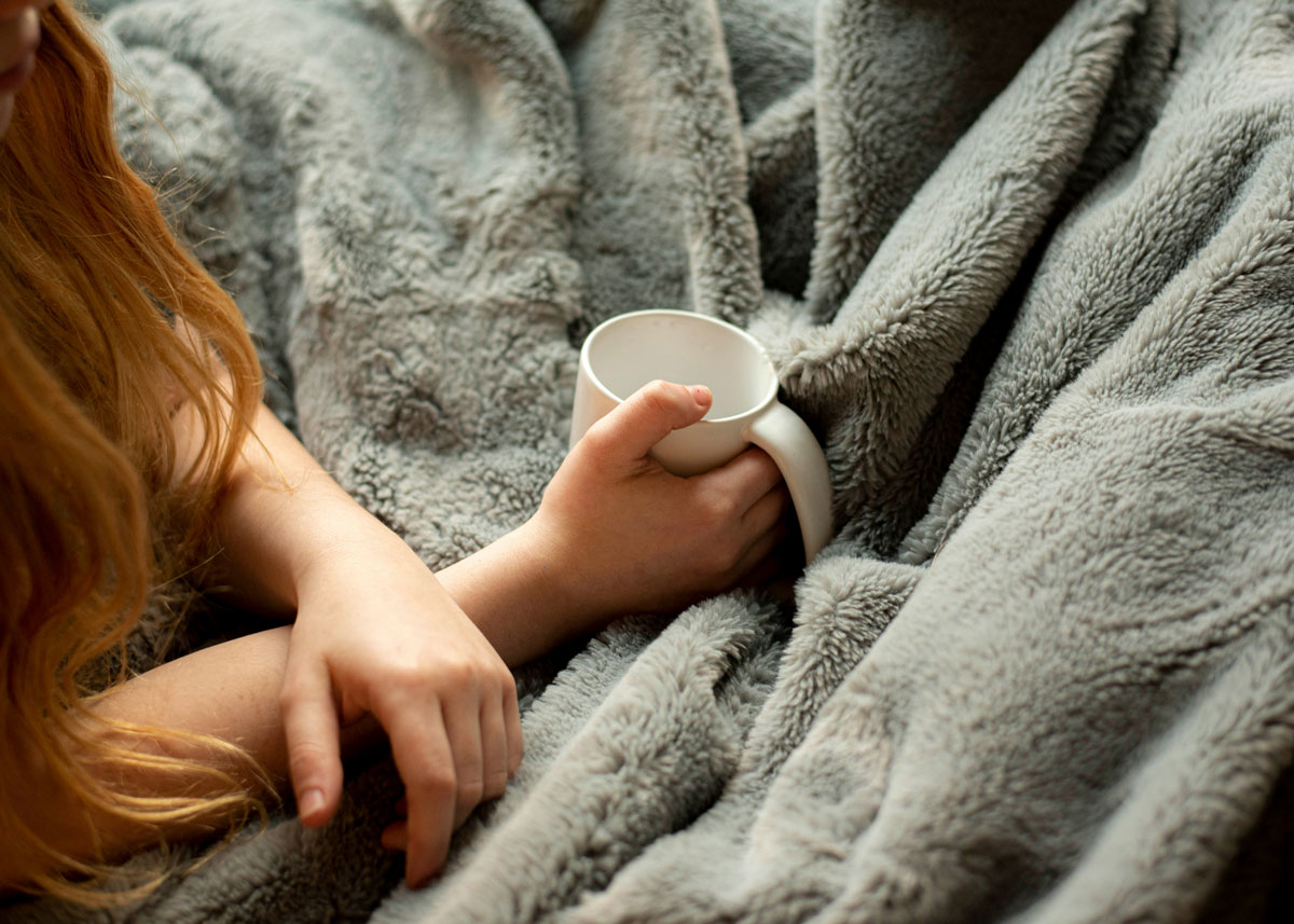 Girl sitting with a mug and a blanket